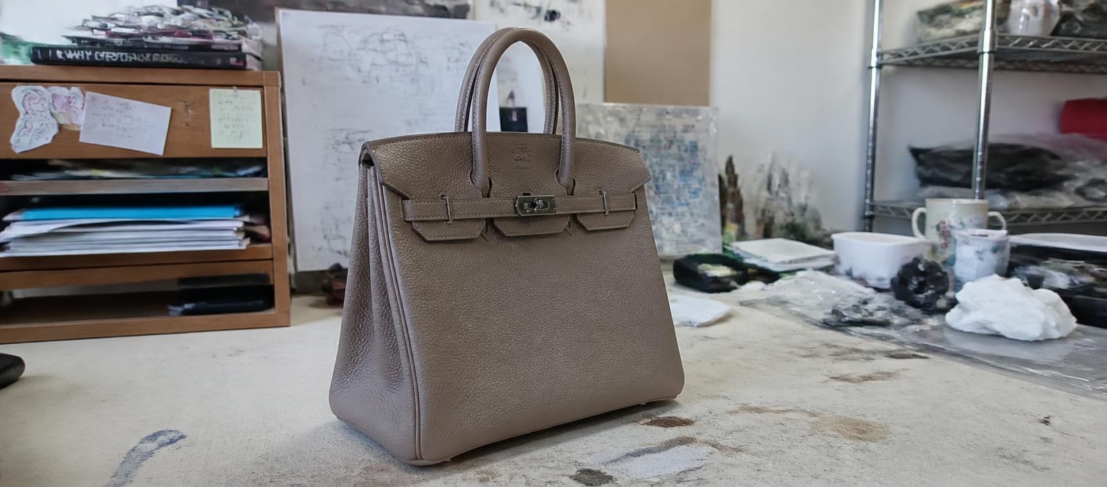 Raw supplier photo of a leather handbag under harsh mixed lighting